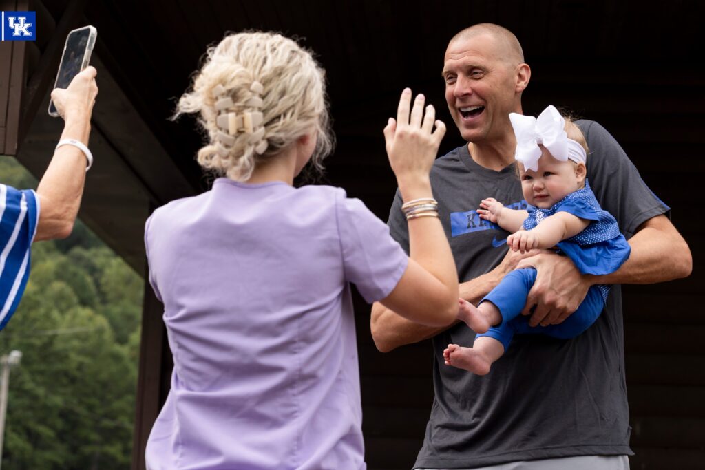 Mark Pope holds a BBN baby, via via Chet White, UK Athletics