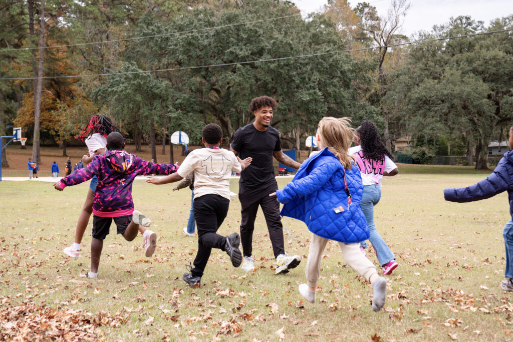 Florida State QB Tommy Castellanos high-fives Astoria Park students after they received their new coats Monday. (Courtesy of FSU Football)