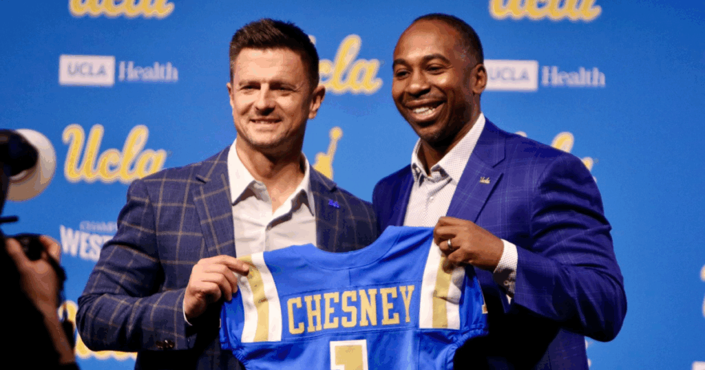 New UCLA head coach Bob Chesney, left, alongside athletic director Martin Jarmond holding a personalized football jersey